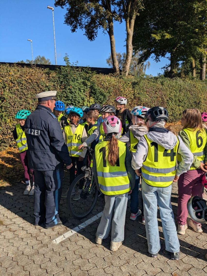 Ein Polizist steht vor mit Warnwesten gekleideten Schülern