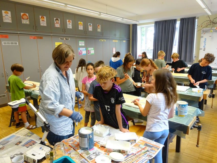 Schulkinder bemalen Zaunlatten mit Pinseln
