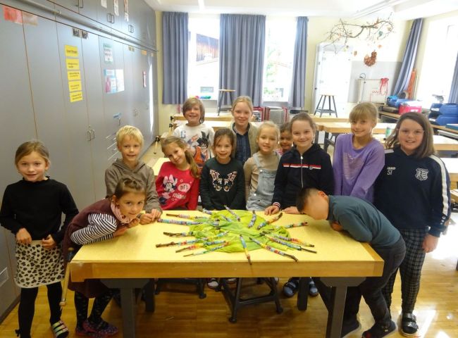Schüler stehen an einem Tisch mit gebastelten Werken