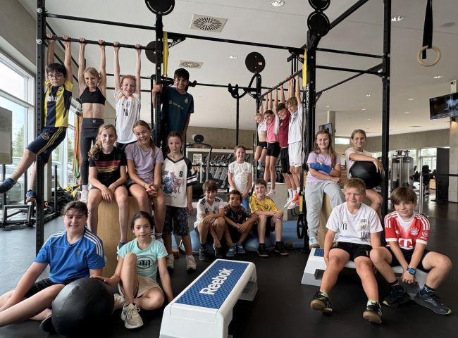 Kinder sitzen vor einem Fitnessgerät