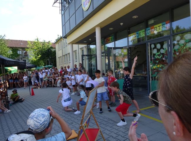 Kinder führen einen Tanz auf dem Schulhof auf