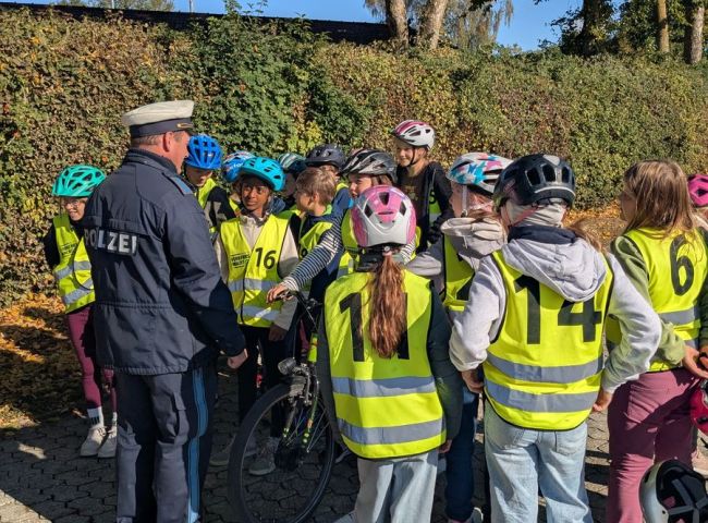 Ein Polizist steht vor mit Warnwesten gekleideten Schülern
