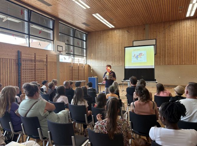 Eltern lauschen einer Präsentation in der Turnhalle
