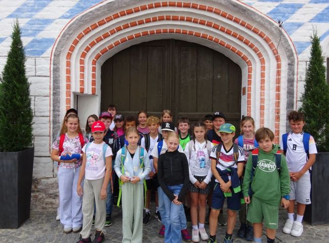 Schulkinder stehen vor einem Torbogen
