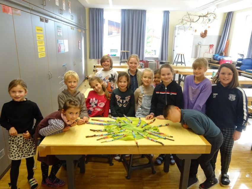 Schüler stehen an einem Tisch mit gebastelten Werken