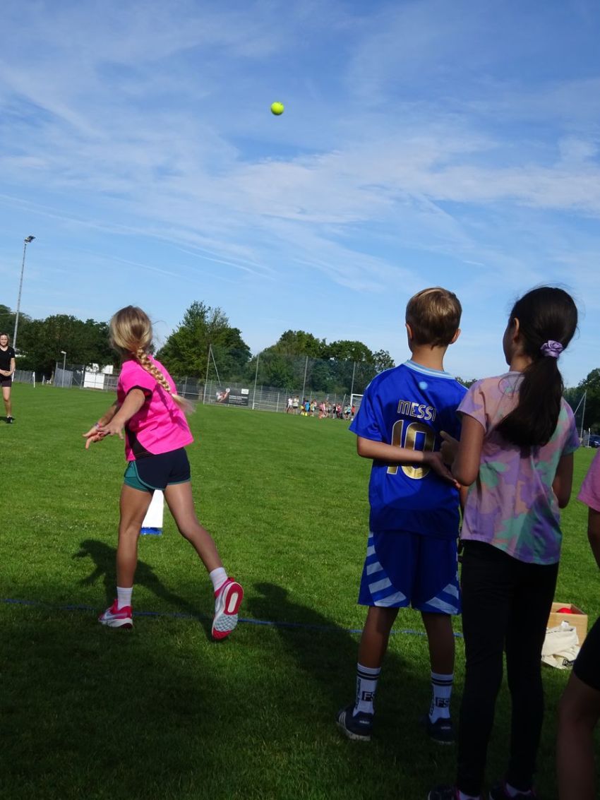 Ein Mädchen wirft einen Ball auf dem Rasen