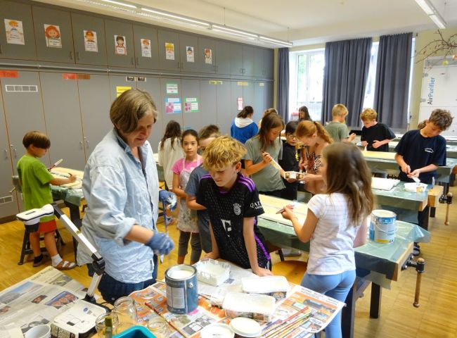 Schulkinder bemalen Zaunlatten mit Pinseln